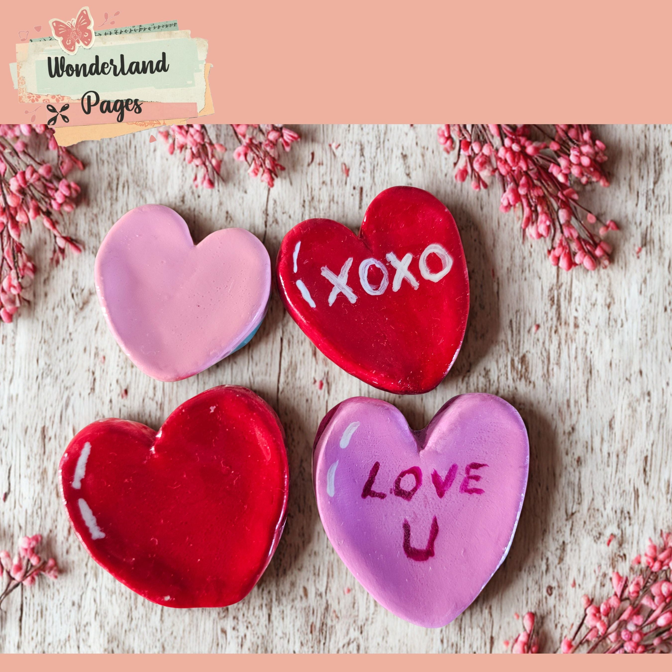 Heart-shaped cookies with 'XOXO' and 'I LOVE U' on a wooden surface with pink flowers.